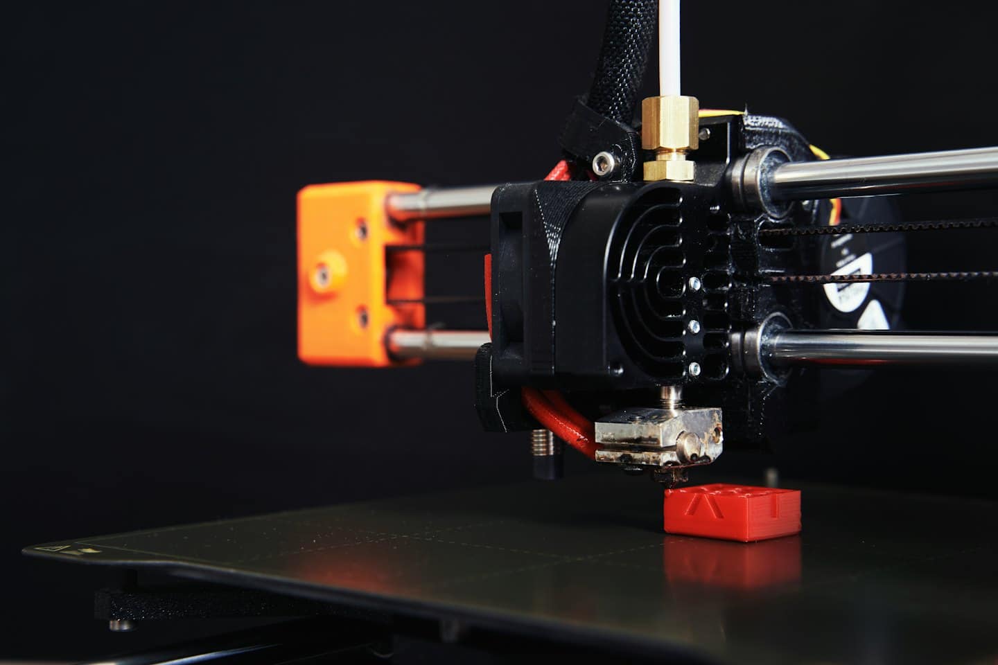 Stampante 3D che costruisce un piccolo oggetto rosso.