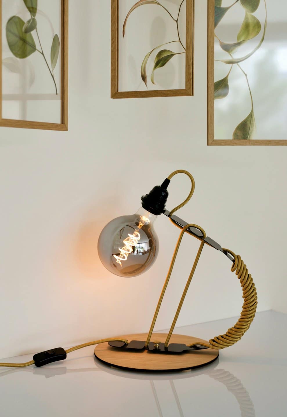 Lampada da scrivania moderna con base in legno su superficie bianca.